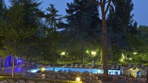 A pool area with lounge chairs, trees, and a night-time setting. - Melia Grand Hermitage (Golden Sands)