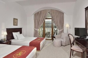 A hotel room with two beds, a TV, a chair, and a balcony with curtains. - Melia Grand Hermitage (Golden Sands)