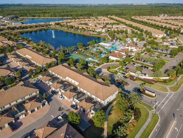 An aerial view of a residential area with houses, a swimming pool, and a tennis court.