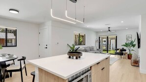 Une cuisine moderne dotée d’un îlot central, de meubles en bois et de luminaires suspendus.