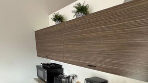 Een moderne keuken met ingebouwde houten kasten, een aanrecht met koffiezetapparaat, broodrooster en andere apparaten.