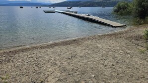 A lake with a dock extending into the water, surrounded by mountains and trees.