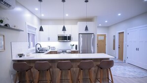 A modern kitchen with white cabinets, stainless steel appliances, and bar stools.