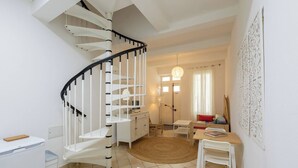 A modern interior with a spiral staircase, a dining area with a round table, and a living space with a sofa and a lamp. - The discreet 18th century (Sérignan)