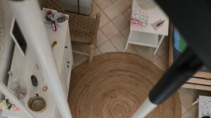 A spiral staircase with a round woven rug at the bottom, white furniture, and a small table with items on it. - The discreet 18th century (Sérignan)
