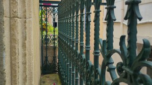 A narrow alley with ornate wrought iron fencing, a stone wall, and a building with a tiled roof in the background. - The discreet 18th century (Sérignan)