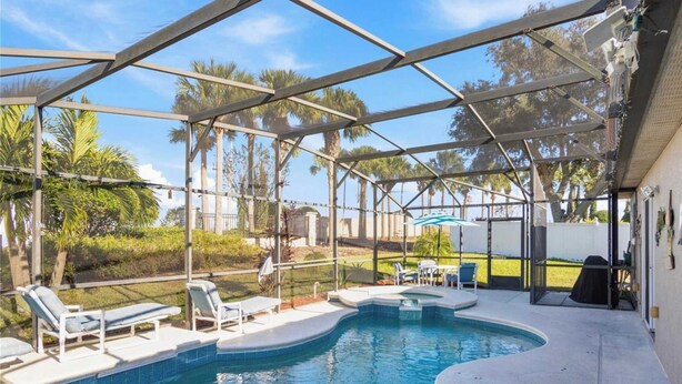 A covered outdoor swimming pool with lounge chairs and a barbecue area. - Magic Oasis Retreat (Davenport)