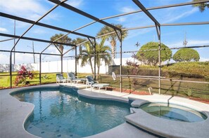 Una piscina techada con sillones de descanso y una bañera de hidromasaje, rodeada de palmeras y vistas del paisaje.