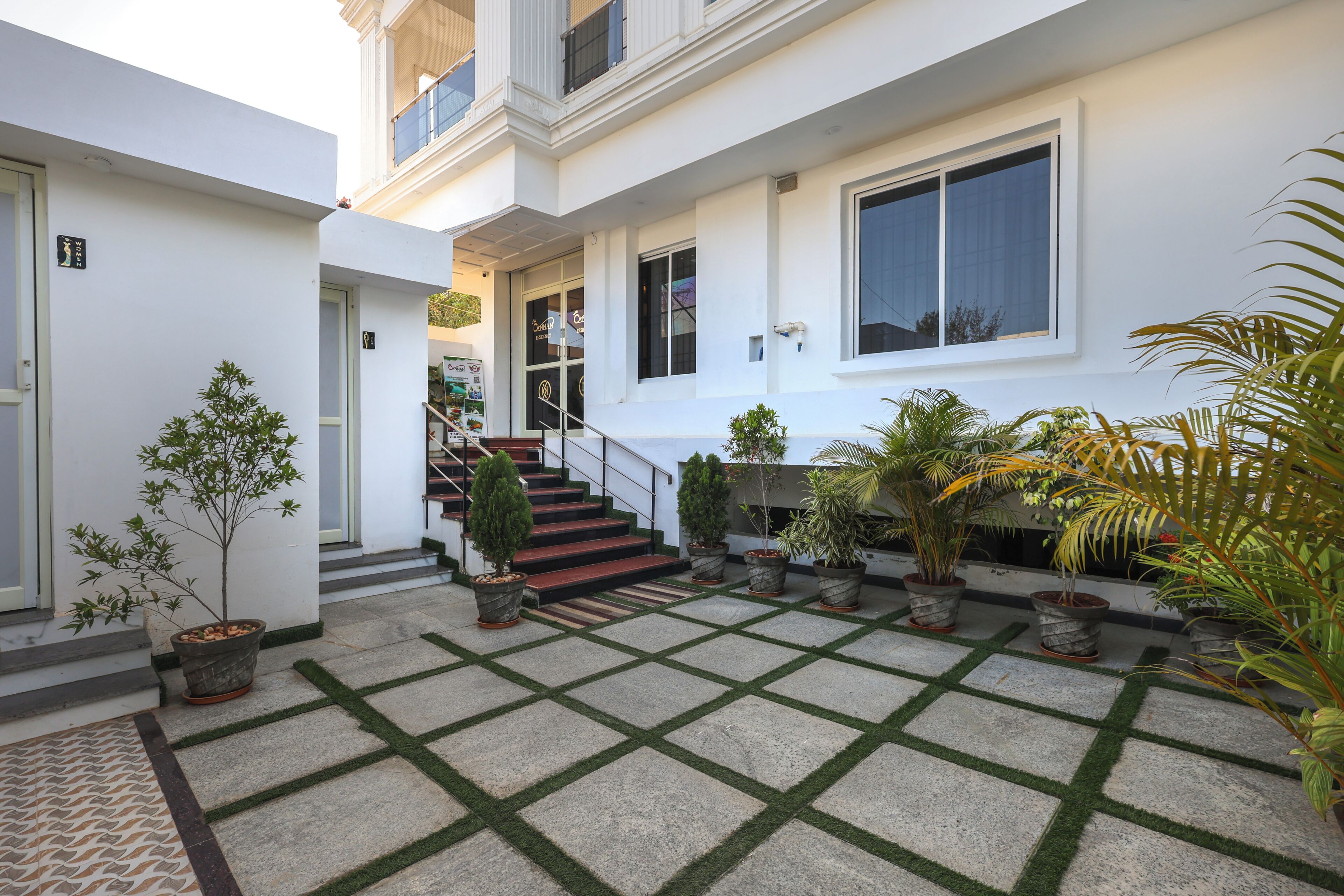 A modern building with a courtyard featuring potted plants and a tiled floor.