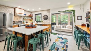 A modern kitchen with a central island, bar stools, and a view to a balcony. - The Horseshoe Hideaway Lake Harmony Cabin w/ Hot Tub & Game Porch (Lake Harmony)
