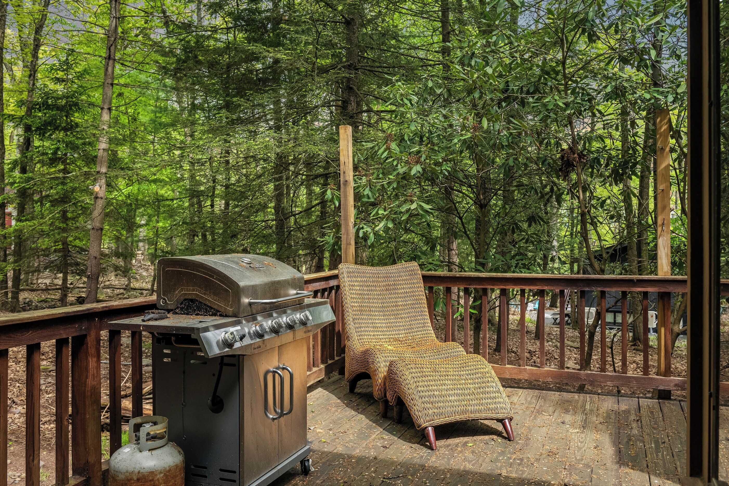 A wooden deck with a barbecue grill and a wicker lounge chair.