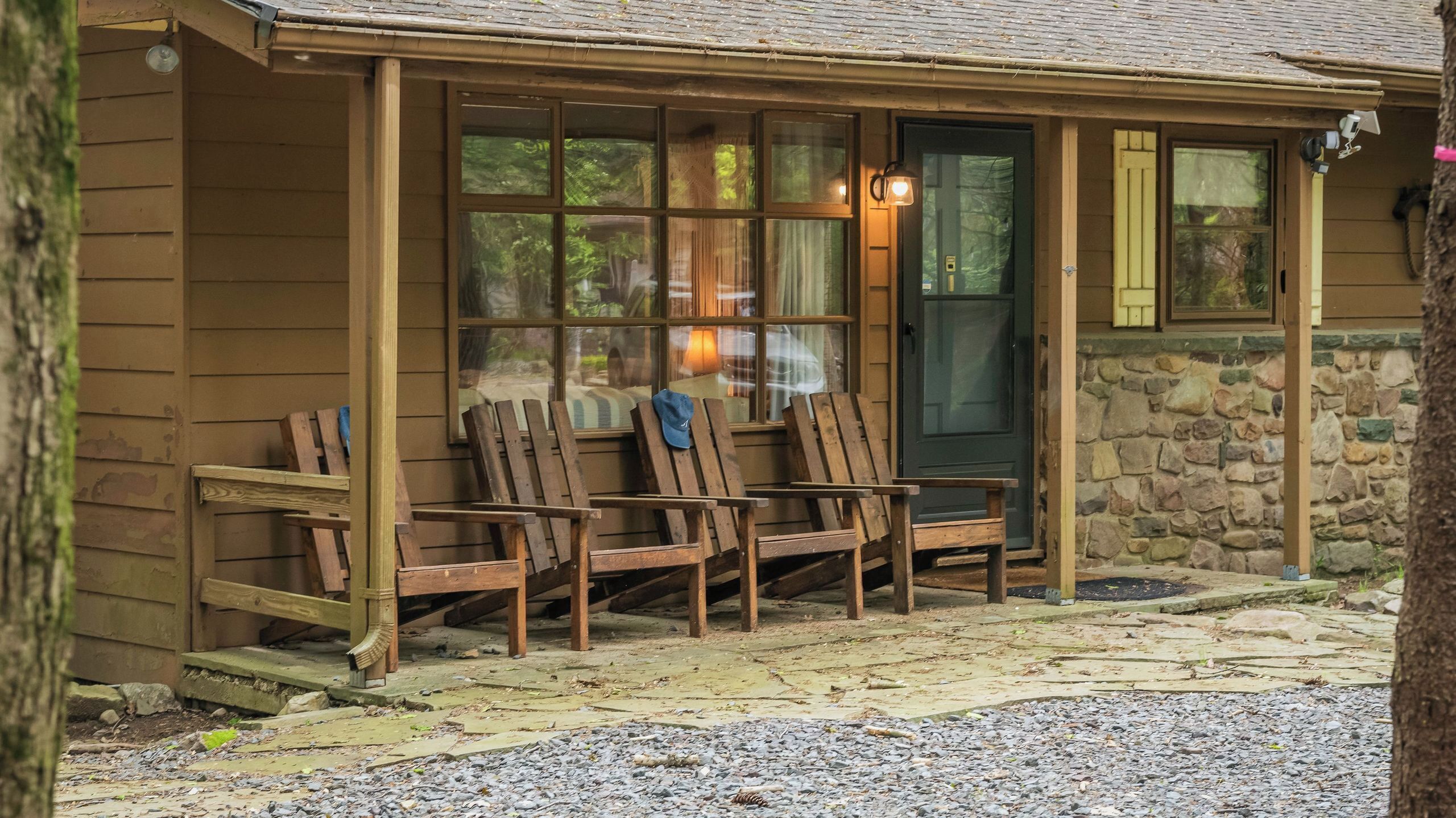 A wooden building with a porch, stone wall, and a door with a window.