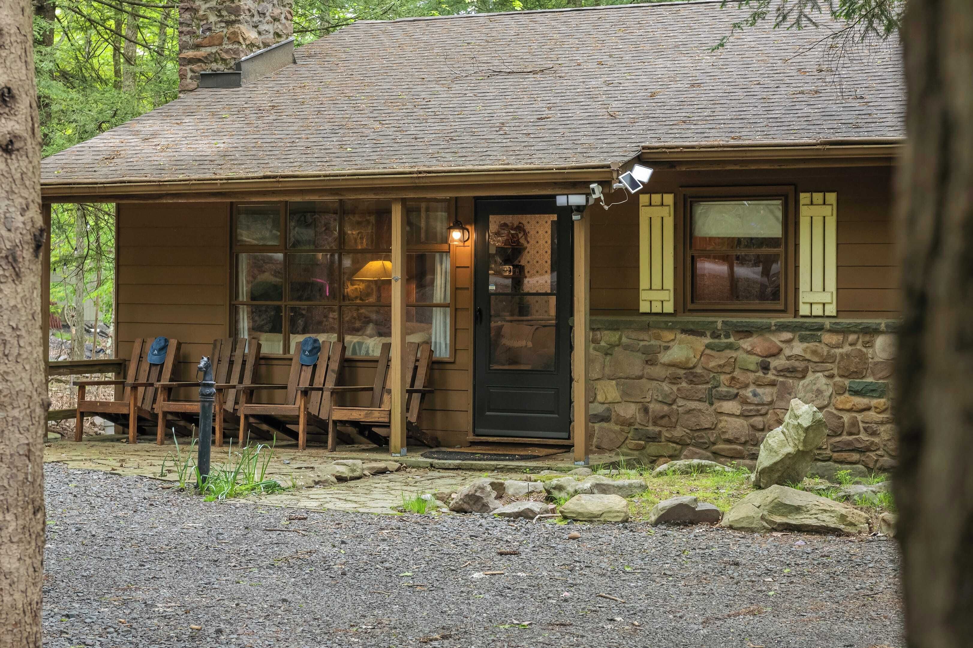 A rustic cabin with a stone exterior, wooden porch, and a door with shutters.