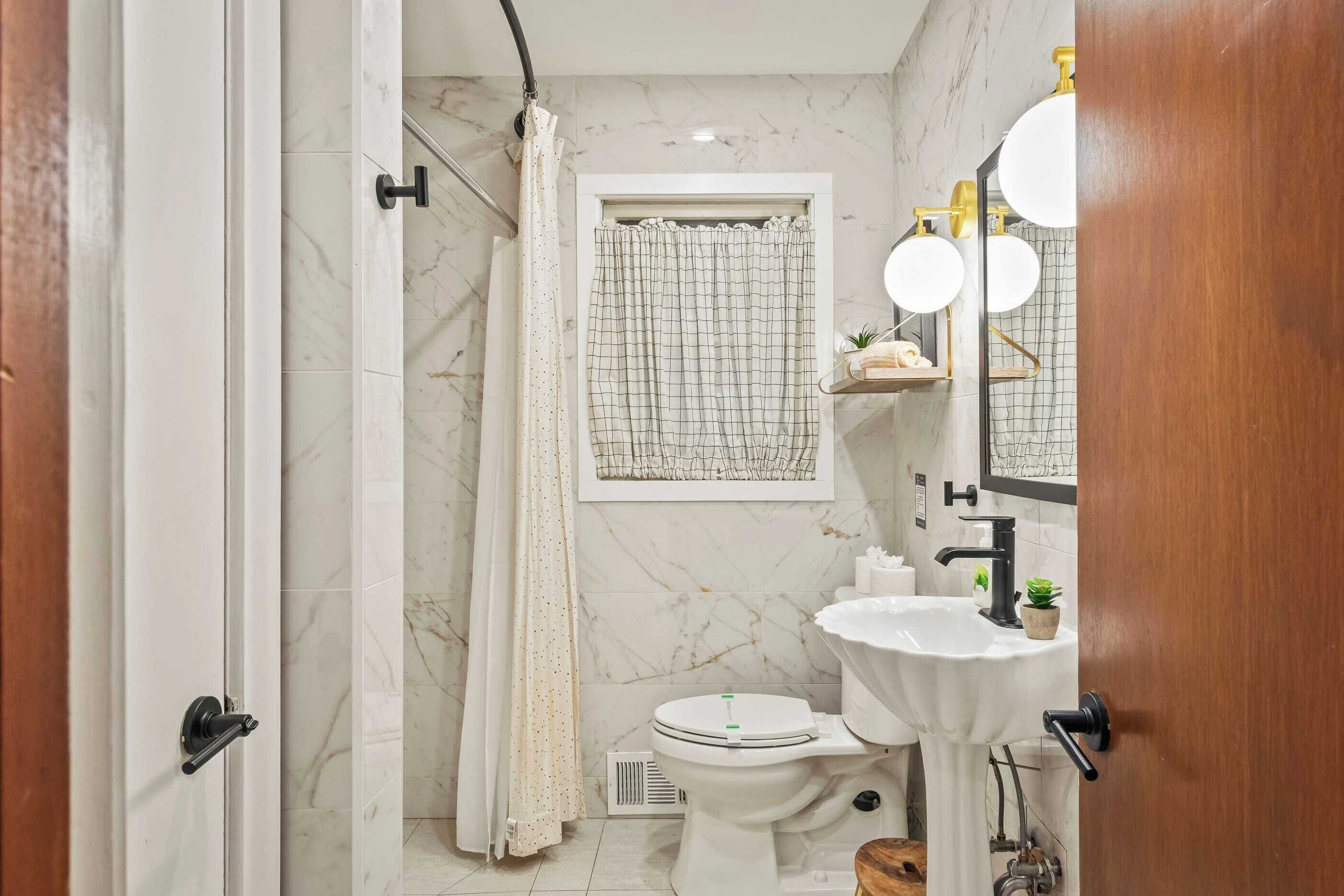 Un baño con inodoro, lavamanos y zona de ducha.
