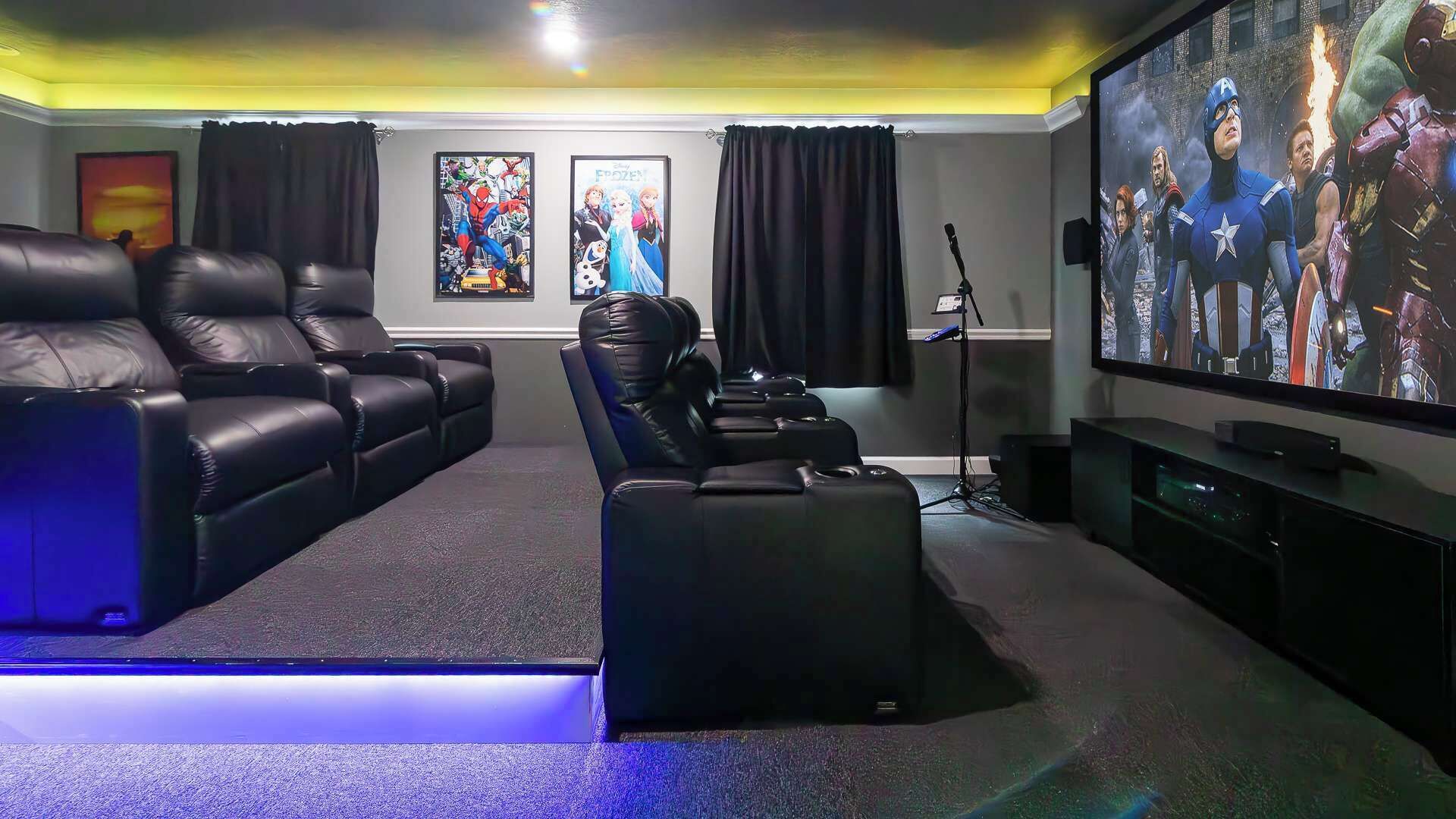 A home theater with leather recliners, a large flat-screen TV, and posters on the wall.