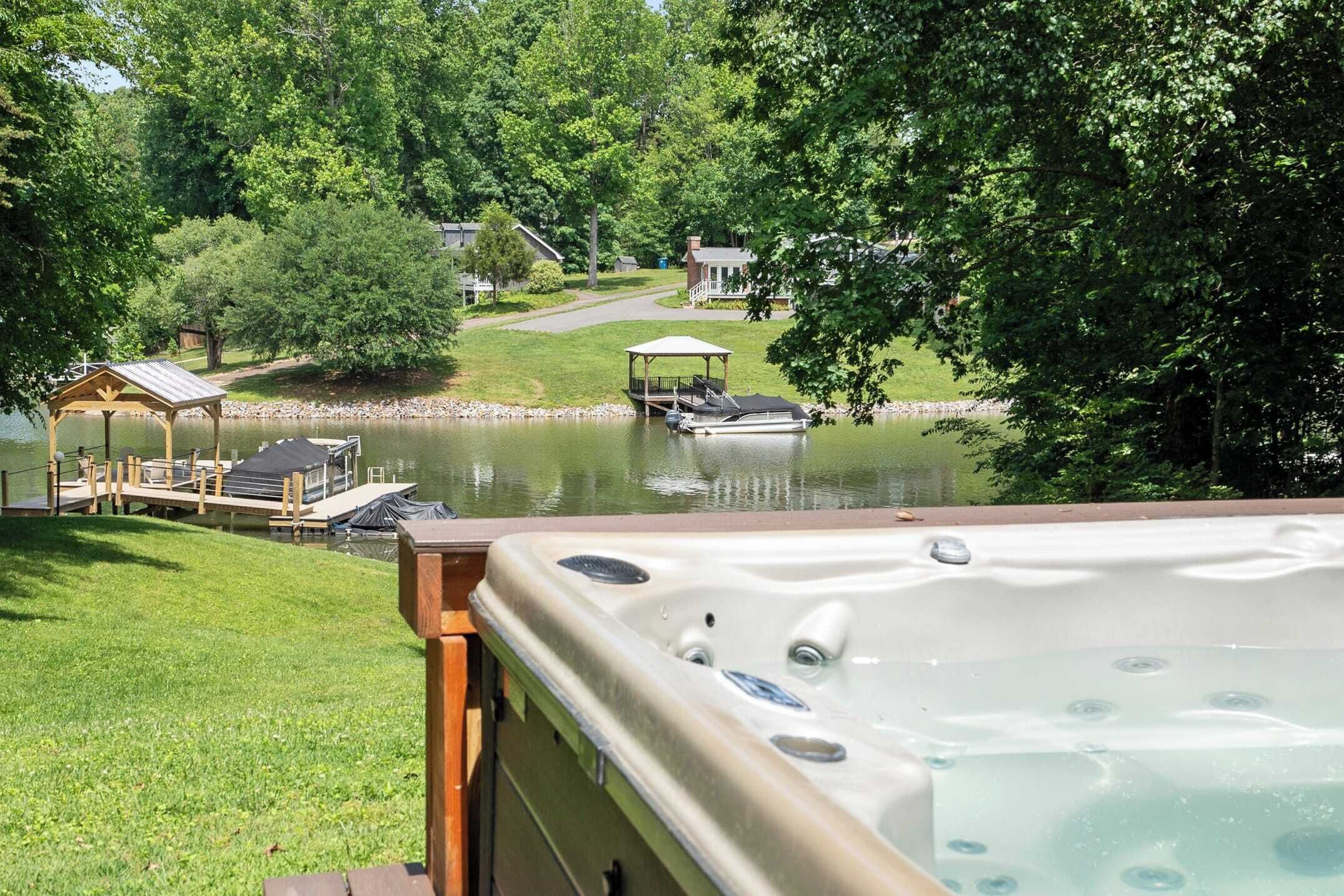 A hot tub with a view of a lake, dock, and gazebo.