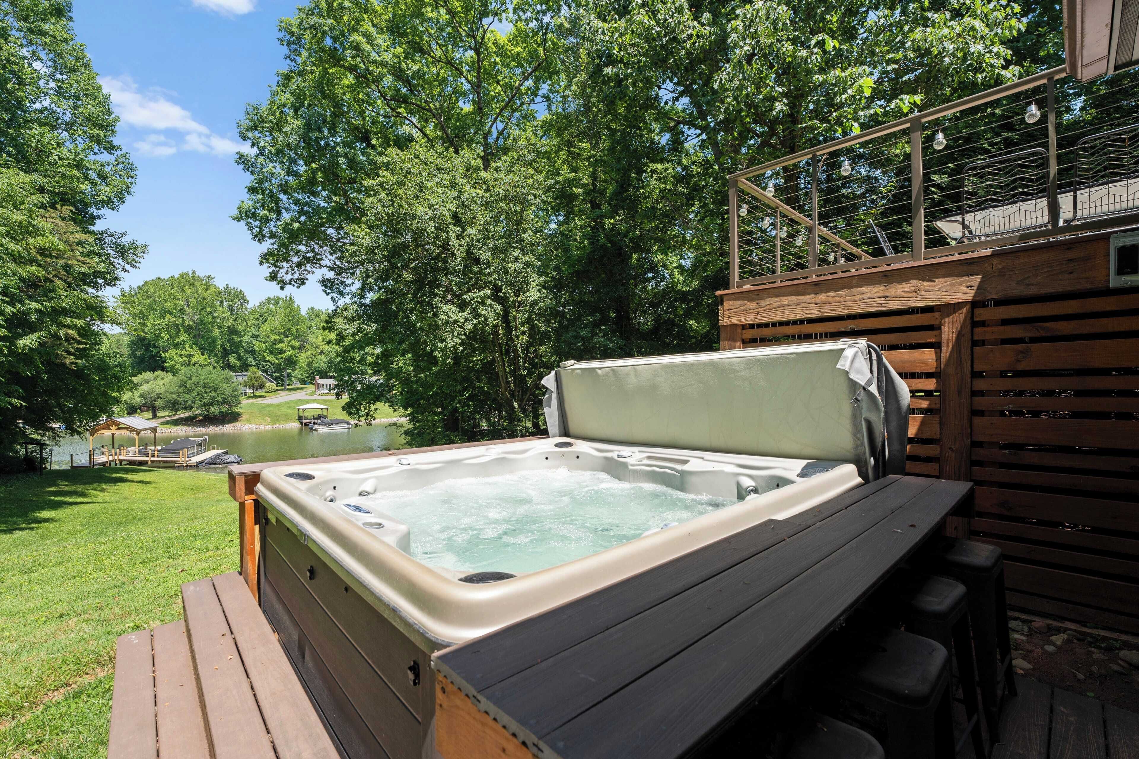 Un jacuzzi en una terraza de madera con vistas a un lago y árboles.