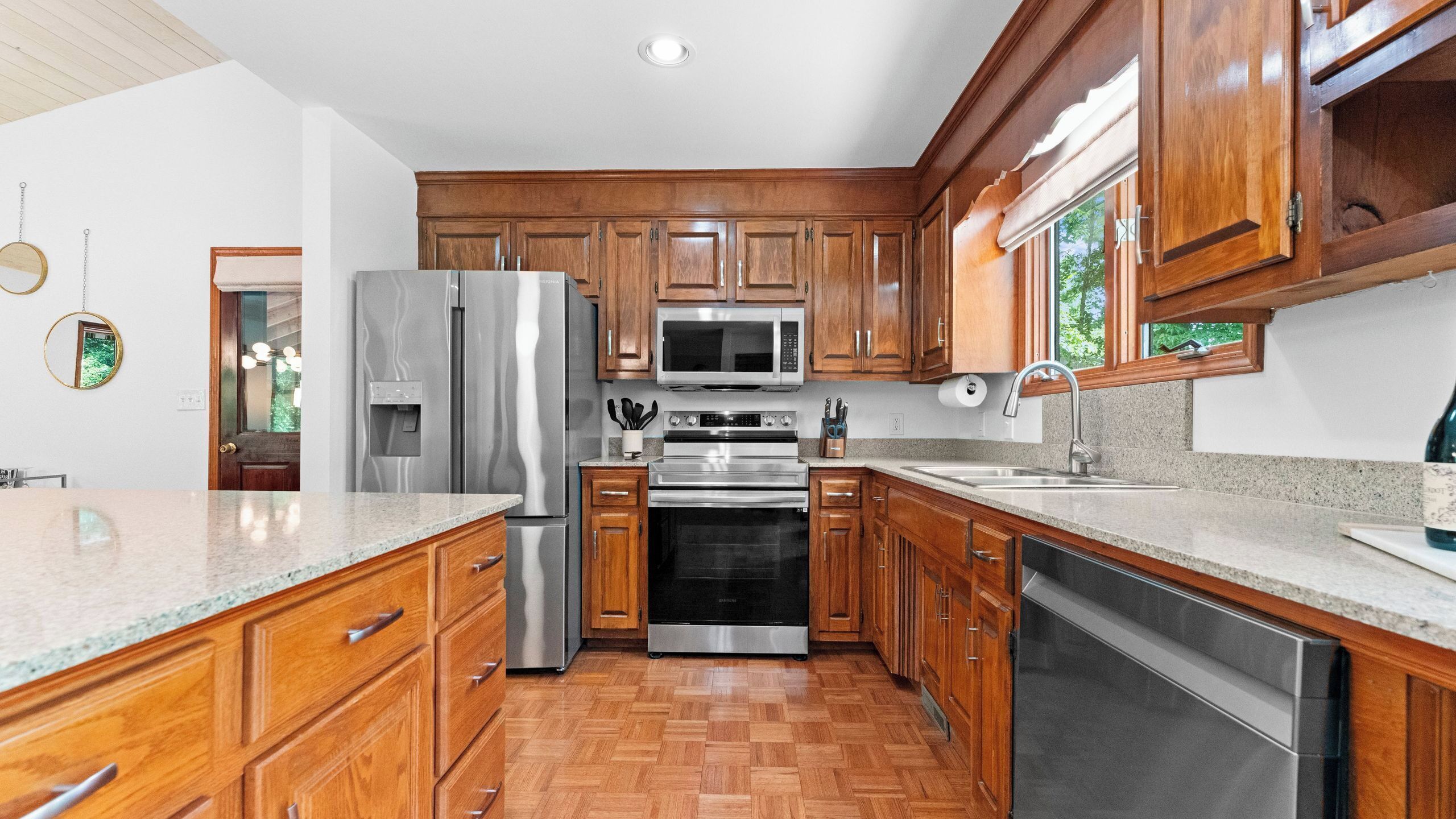 A modern kitchen with wooden cabinets, stainless steel appliances, and a granite countertop.