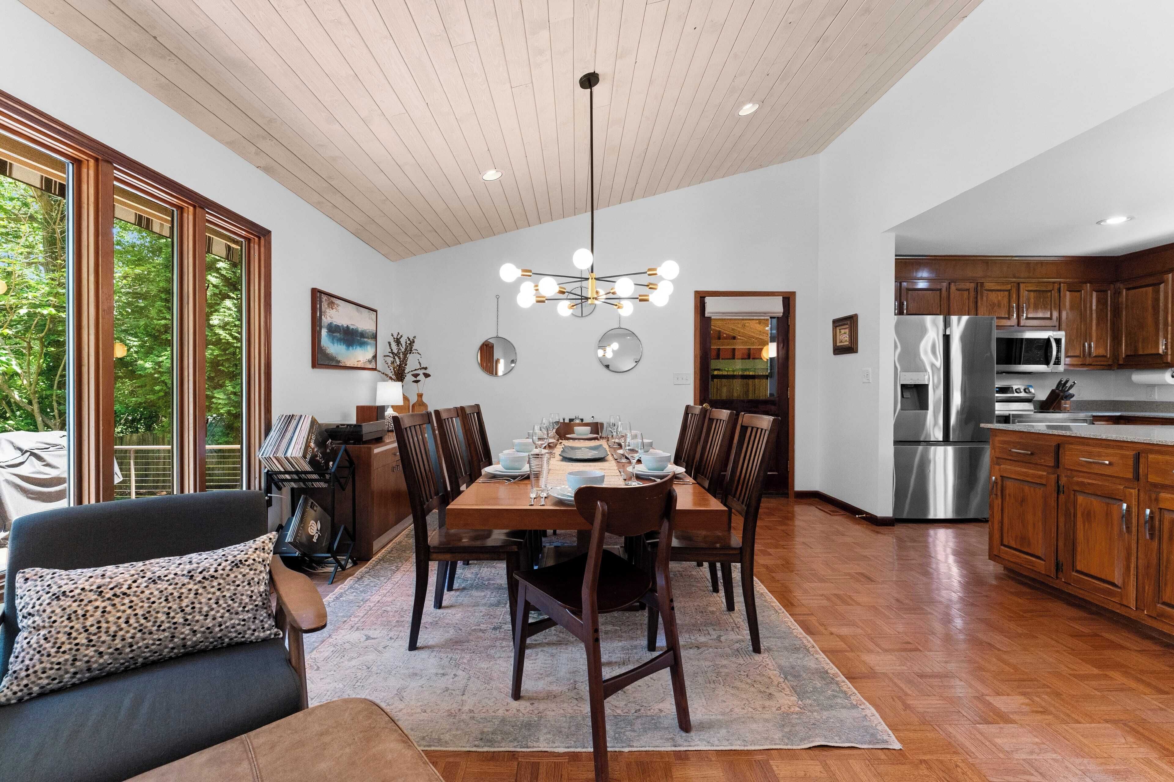 Una cocina moderna con armarios de madera, electrodomésticos de acero inoxidable y un comedor con mesa y sillas de madera.
