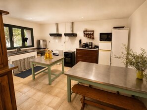 Une cuisine compacte équipée d’un évier, d’une cuisinière, d’un four à micro-ondes et d’un petit coin repas avec un banc.