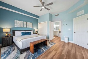 A bedroom with a bed, bedside tables, a ceiling fan, and a bathroom visible through an open door.