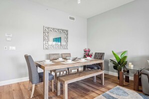 A dining area with a wooden table, chairs, a bench, and a decorative mirror on the wall.