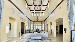 A spacious lobby with a marble-patterned floor, a central seating area, and a high ceiling with wooden beams and skylights. - Minutes to Magic (Orlando)