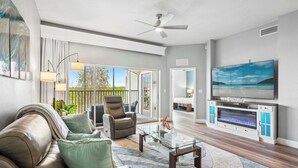 A modern living room with a leather sofa, glass coffee table, and a flat-screen TV. - Minutes to Magic (Orlando)