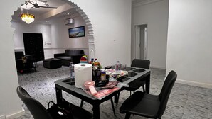 Une salle de conférence moderne avec un sol en marbre, des chaises noires, une table en verre et un lustre.