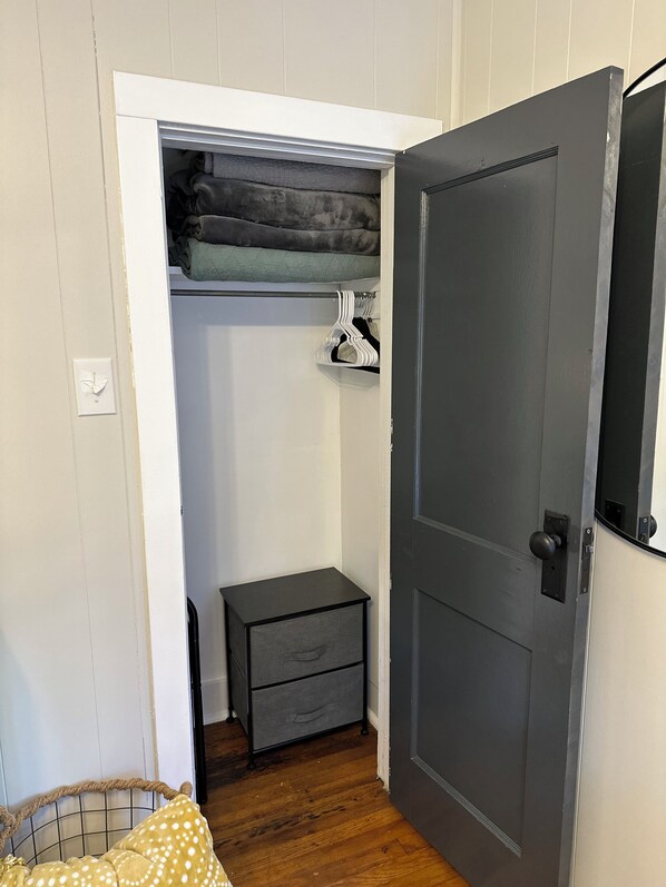 A room with a wardrobe, a small bedside table, and a bed with a polka-dotted blanket.