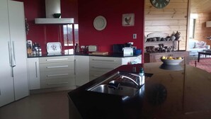 Een keuken met witte kasten, een zwart aanrecht en een rode wand. Er is een raam met uitzicht op het buiten.