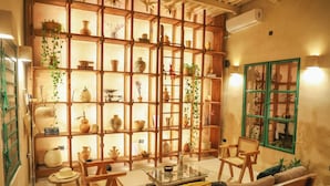 A cozy living room with a wooden bookshelf filled with decorative items, a glass coffee table, and comfortable seating.