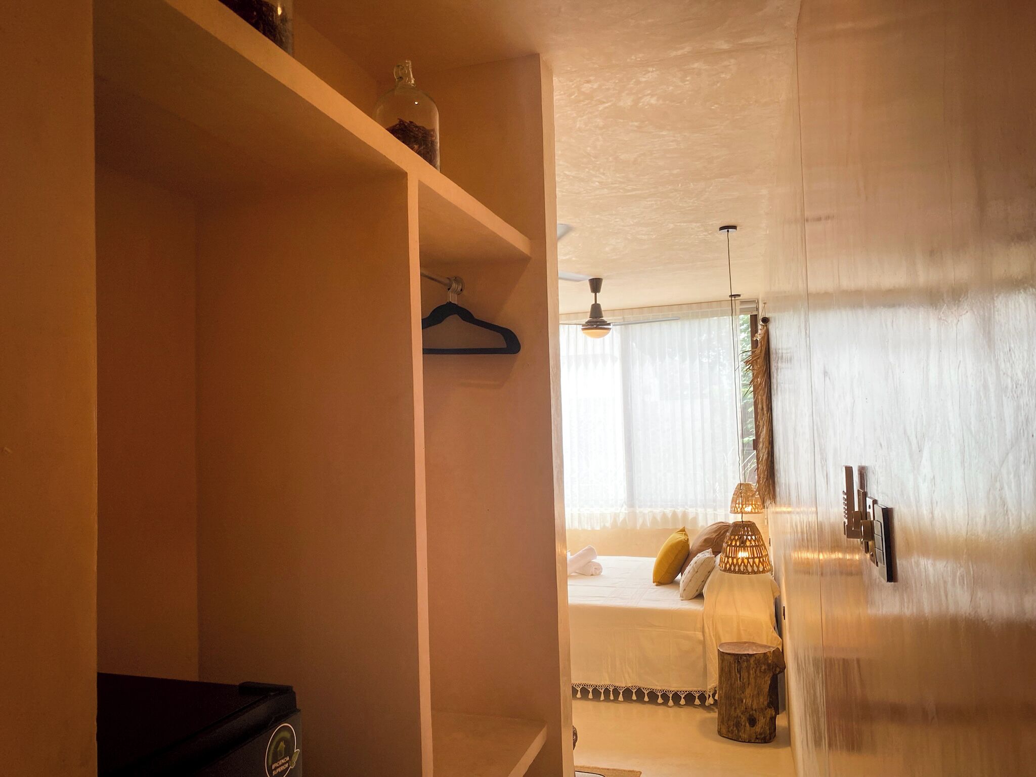 Una habitación de hotel con una cama, una lámpara colgante y una mesita de madera.