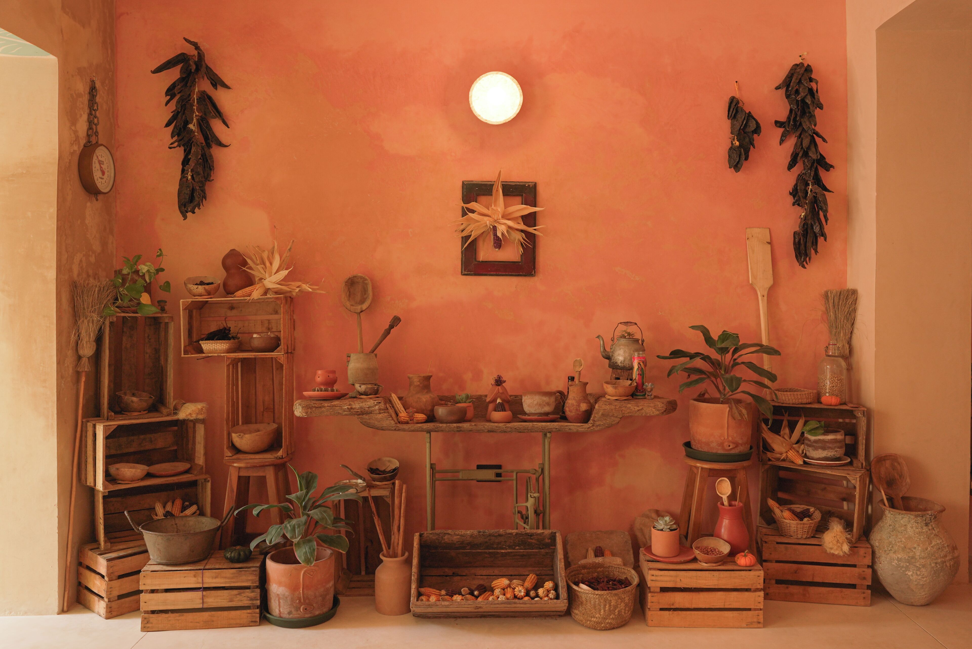 Une cuisine rustique agrémentée de caisses en bois, de plantes en pot et d’ustensiles de cuisine anciens.