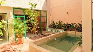 Ein Wellnessbereich mit Whirlpool, umgeben von Kübelpflanzen und einer Sitzecke.