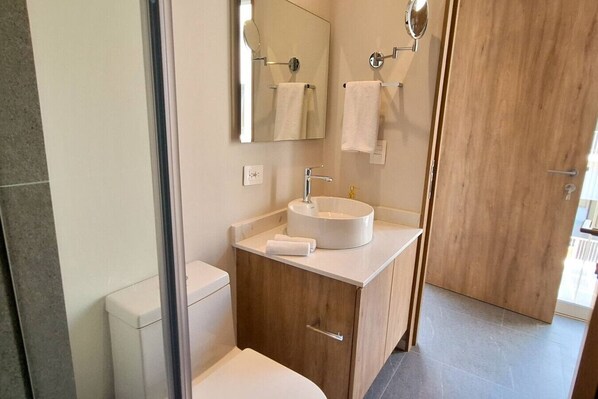 Un baño moderno con lavamanos blanco, mueble de madera y un espejo.