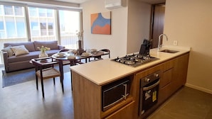 Une cuisine moderne dotée d’un îlot central, d’un coin repas avec un canapé et d’une grande fenêtre offrant une vue dégagée.