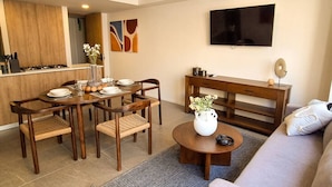 Un salon moderne comprenant un coin repas, un canapé, une table basse et un téléviseur fixé au mur.