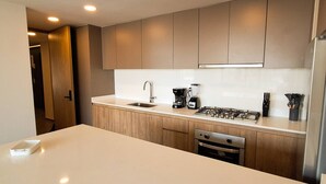 A modern kitchen with wooden cabinets, a stainless steel sink, a coffee maker, and a gas stove.