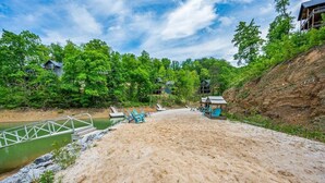 A sandy beach with a bridge, a pool, and a building with a balcony. - Cozy Current Lake Cabin! +Pet Friendly +Game Loft! (Sevierville)