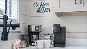 A kitchen counter with a coffee maker, a coffee pot, two white mugs, and a jar of coffee pods. - Cozy Current Lake Cabin! +Pet Friendly +Game Loft! (Sevierville)