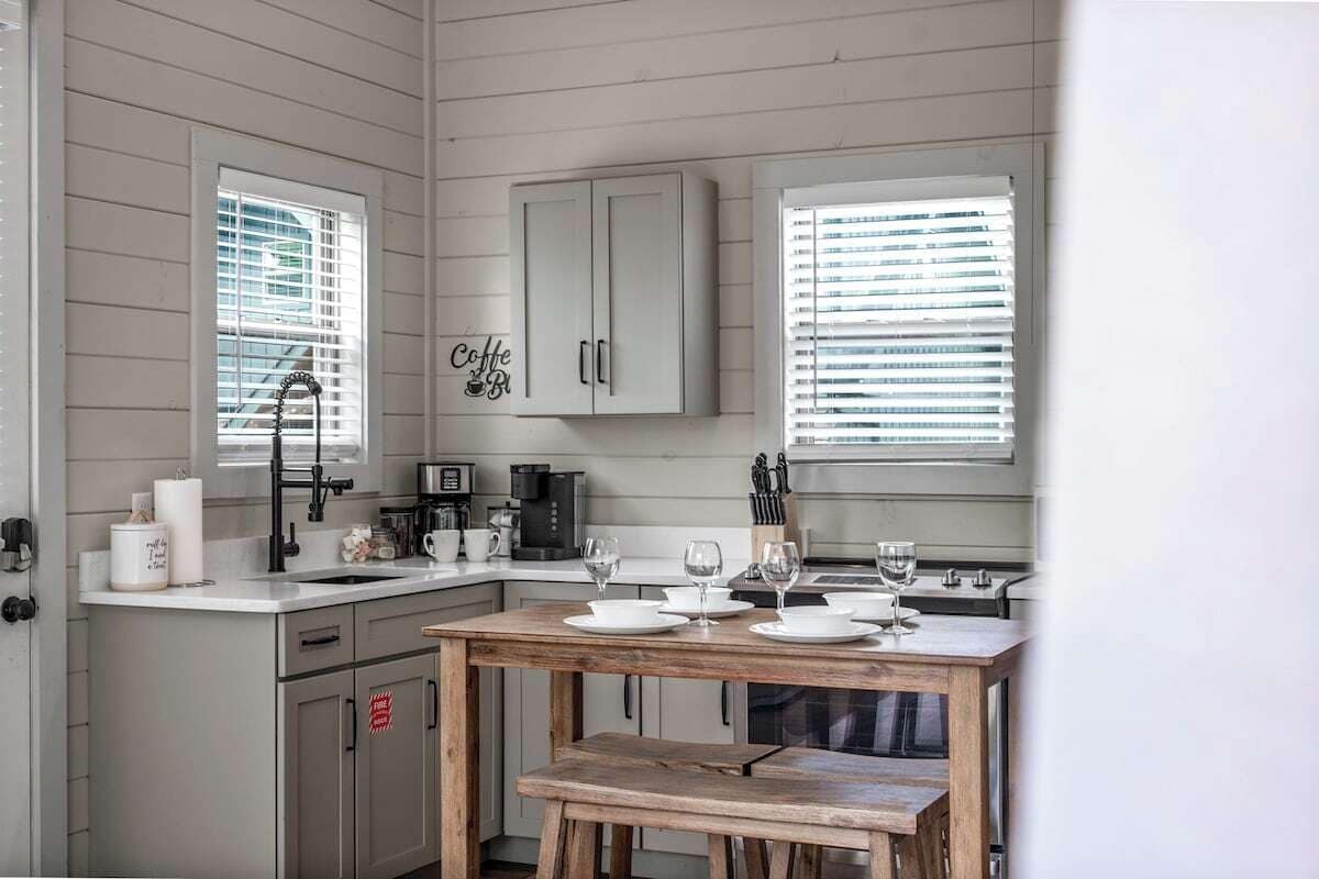 A kitchen with a wooden table set for dining, a coffee machine, and a cabinet with a sign.