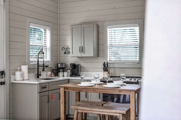 A kitchen with a wooden table set for dining, a coffee machine, and a cabinet with a sign.