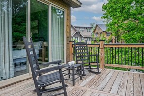A wooden deck with outdoor furniture, including chairs and a table, overlooking a residential area with houses and greenery. - Cozy Current Lake Cabin! +Pet Friendly +Game Loft! (Sevierville)