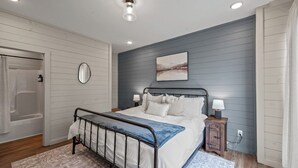 A bedroom with a bed, bedside tables, a mirror, and a painting on the wall. - Cozy Current Lake Cabin! +Pet Friendly +Game Loft! (Sevierville)