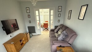 A living room with a sectional sofa, a TV, and a wooden coffee table. - 3 bedroom spacious home Parking and WiFi sleeps 5 (Bexleyheath)