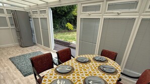 An outdoor dining area with a table set for four, surrounded by chairs, under a covered patio. - 3 bedroom spacious home Parking and WiFi sleeps 5 (Bexleyheath)