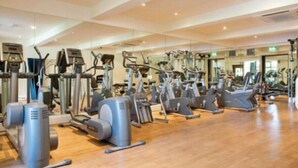 Une salle de sport équipée de divers appareils de cardio, notamment des tapis de course et des vélos elliptiques, disposés en rangées.