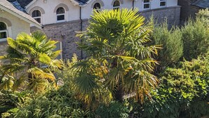A historic building with multiple chimneys, surrounded by lush greenery and a mountainous backdrop. - Spacious house, high in the hills, stunning views, on-site indoor pool, bar, gym (Keswick)