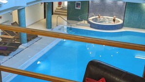 A pool area with a glass barrier, a lounge chair, and a red patterned pillow. - Spacious house, high in the hills, stunning views, on-site indoor pool, bar, gym (Keswick)